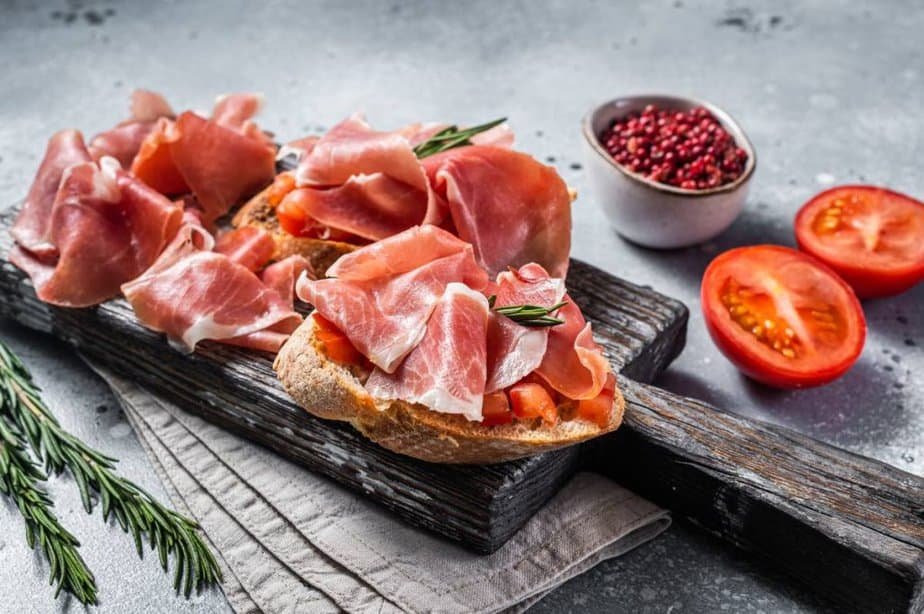 Spanish Tapas - Toast with tomatoes and cured Slices of jamon iberico ham on wooden board.