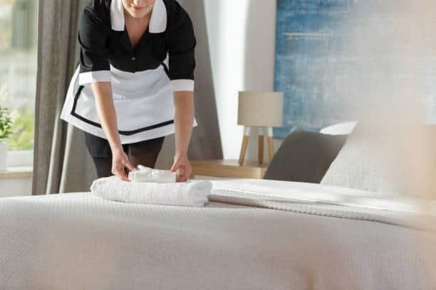 Young maid laying fresh towels on a bed in hotel room hotels spain